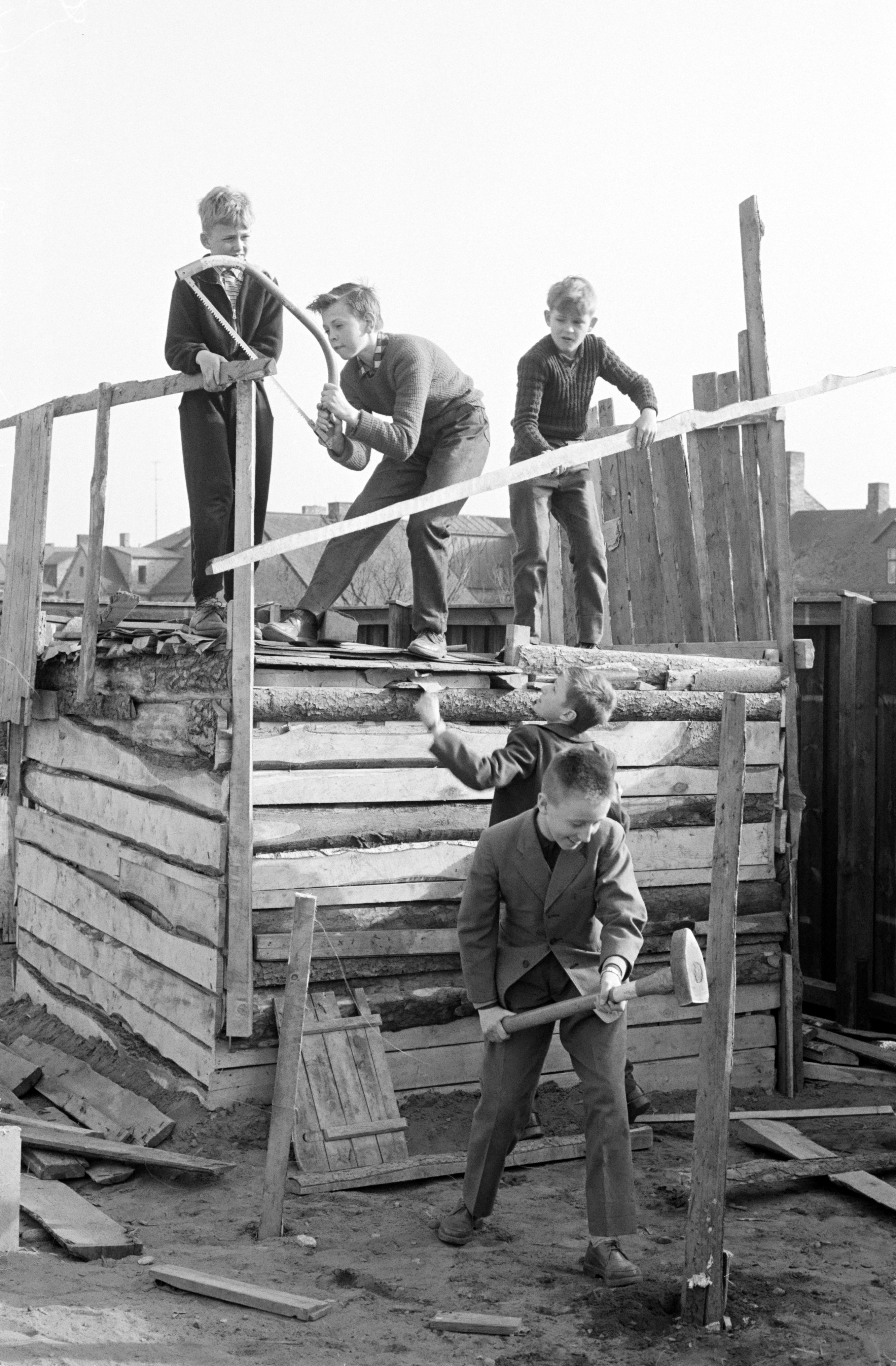 Gammalt svartvitt foto på glada barn som leker och bygger i trä.